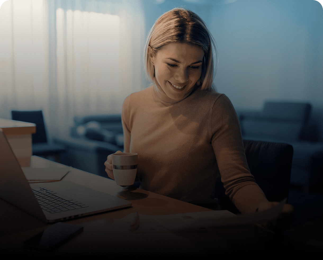 Woman smiling, holding a coffee mug.