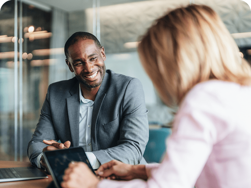 Smiling colleagues discussing work at a meeting.