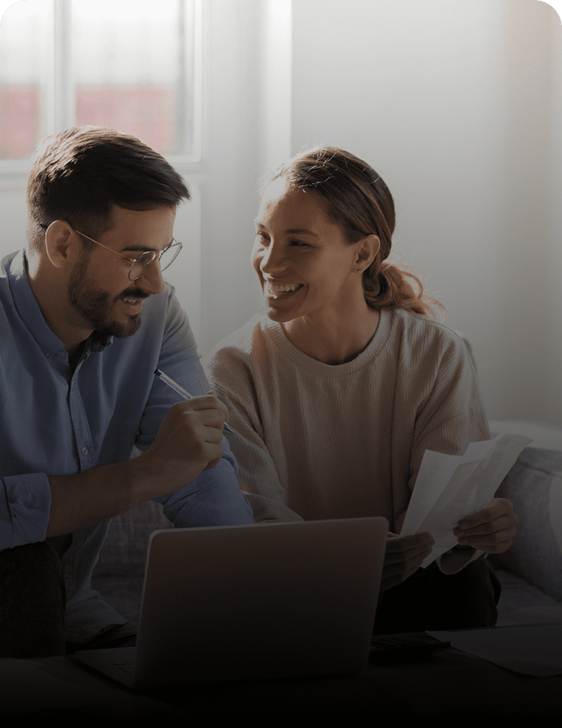 Smiling couple working on laptop together.